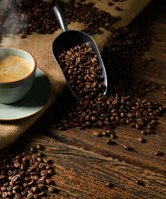 Cup of coffee with smoke and coffee beans on old wooden background